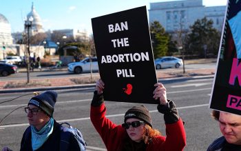 Demonstrators hold signs during a protest outside the U.S. Department of Health and Human Services in Washington Jan. 22, 2026, calling on President Donald Trump's administration to ban the abortion pill.