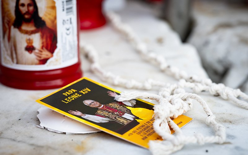 Devotional items are found next to the statue of St. John Paul II Oct. 14, 2026, in front of Rome's Gemelli hospital where Pope Leo XIV is recovering from surgery during which doctors removed his lower right lung to treat a cancerous tumor.