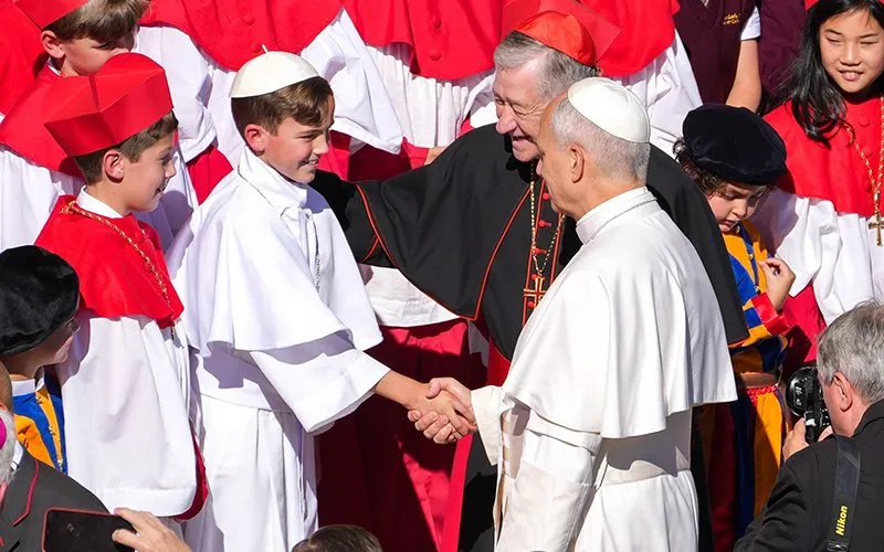Chicago Cardinal Blase J. Cupich looks on as Pope Leo XIV greets fourth-grader Augie Wilk, who was elected "Pope Augustine" in a mock conclave at Our Lady of Mount Carmel Academy in Chicago, during the pope's weekly general audience in St. Peter's Square at the Vatican Oct. 8, 2025.