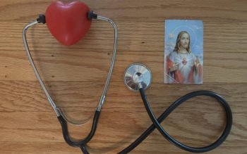 A stethoscope and a prayer card with the image of the Sacred Heart of Jesus.