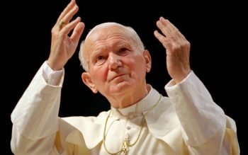 St. John Paul II raises his hands in the air.
