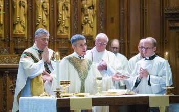 A bishop and several priests celebrate Mass in a church.
