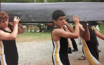 Boys carry a boat on their shoulders.
