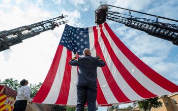 A man stands in front of a large American flag.